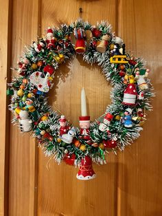 a christmas wreath hanging on a door with ornaments around it and a lit candle in the center