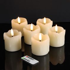 six lit candles with remote control on black surface