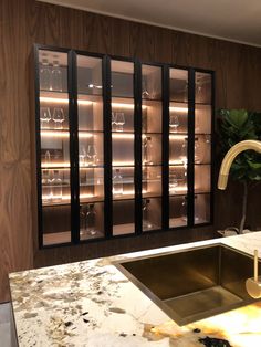 a kitchen with marble counter tops and black glass doors on the wall, next to a sink