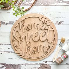 a wooden sign that says home sweet home next to some paint and brushes on a table