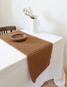 a table with a white vase and brown plate on it