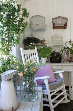 a white table topped with lots of potted plants on top of a wooden floor