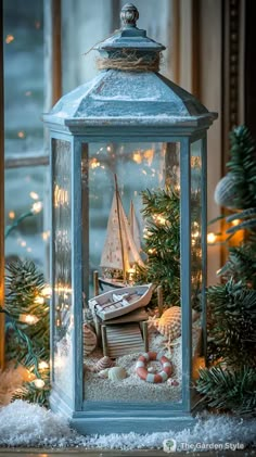 a lantern with a sailboat and other items in it sitting on snow covered ground