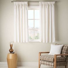 a chair sitting in front of a window next to a vase