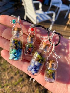 four small glass bottles filled with different types of rocks and gravel, sitting on top of a person's hand