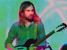 a man with long hair playing an electric guitar