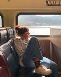 a woman sitting on a train seat with her feet up and looking out the window