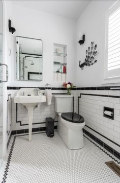 a bathroom with black and white tile flooring and walls, along with a toilet and sink