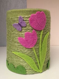 a green basket with pink flowers and butterflies painted on the side, sitting on a table