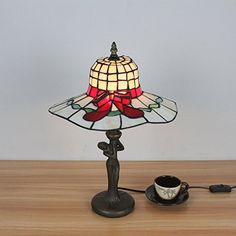 a lamp that is sitting on top of a table next to a coffee cup and saucer