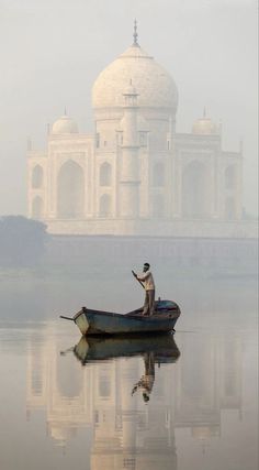 a man on a boat in front of the tajwalar mosque, india