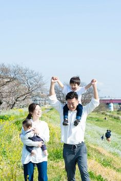 a man carrying a child on his shoulders while standing next to a woman in a field