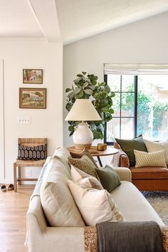 a living room filled with furniture and a lamp on top of a wooden table in front of a window