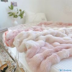 a bed with pink and white fur on it, next to a pair of scissors