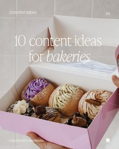 a person holding up a pink box filled with different types of doughnuts and pastries