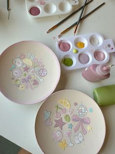 two plates with designs painted on them next to paintbrushes and other art supplies