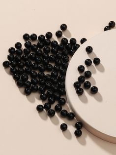 some black beads are laying on top of a white plate next to a cutting board