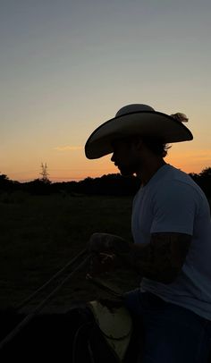 a man riding on the back of a horse wearing a cowboy hat and holding something in his hand