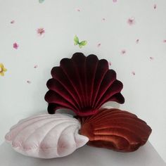 two decorative seashells sitting on top of a white table with pink flowers in the background