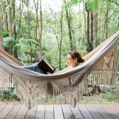 a woman sitting in a hammock reading a book