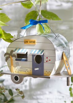 an ornament shaped like a camper is hanging from a branch with leaves