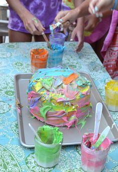 two women are decorating a cake with colorful icing and sprinkles