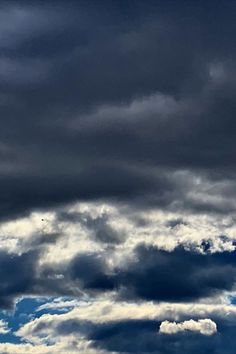 an airplane is flying in the sky with dark clouds behind it and blue skies above