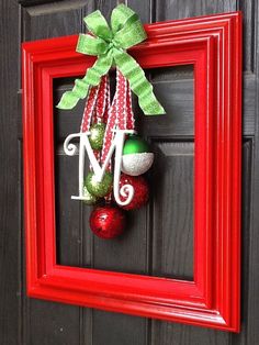 a red frame with a green bow and ornaments hanging on it's front door