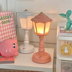 a pink pig lamp sitting on top of a table next to a book and other items