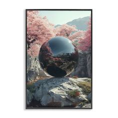 a black ball sitting on top of a rock next to trees with pink flowers in the background