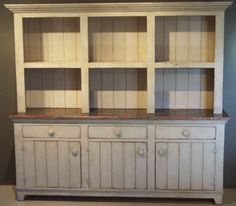 an old white china cabinet with wooden shelves