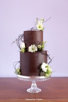 a three layer chocolate cake with white flowers on top