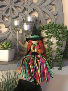 a colorful doll sitting on top of a shelf next to succulents and potted plants