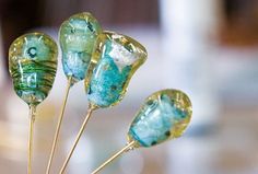 four glass lollipops sitting on top of each other in front of a table