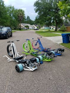 several bicycles are laying on the ground in front of some trash cans and parked cars