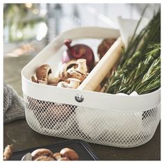 a basket filled with mushrooms and greens on top of a counter next to a plate