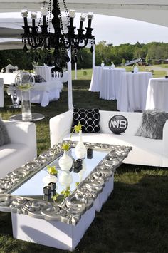 a white couch sitting on top of a lush green field next to a chandelier