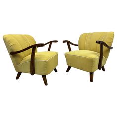 a pair of yellow chairs with wooden arms