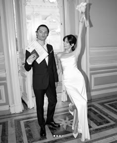 a man and woman in formal wear standing next to each other holding up paper flowers