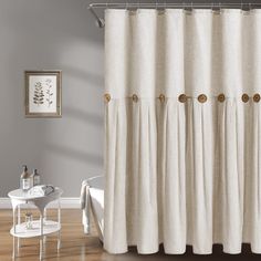 a white shower curtain with gold hardware on the top and bottom, in a bathroom