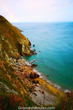 an ocean view from the top of a hill with rocks and grass on it,