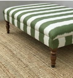 a green and white striped bench sitting on top of a carpeted floor next to a wall