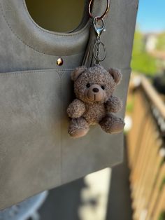 a brown teddy bear hanging from the side of a purse with a keychain