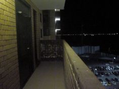 an empty balcony at night with cars parked in the parking lot