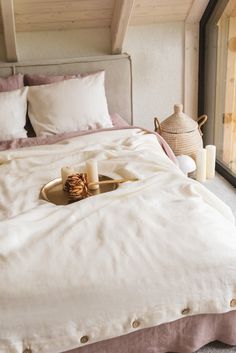 a bed with white linens and pillows in a bedroom next to a large window