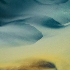 a blurry image of rocks and water in the ocean with blue, yellow and green colors