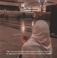 a woman in a white veil sitting on the ground with her head covered by a shawl