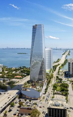 an aerial view of a tall skyscraper next to the ocean with cars and buildings around it