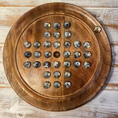 a wooden plate with metal rivets on top of a wood table next to a wall