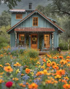 a blue house surrounded by flowers and trees